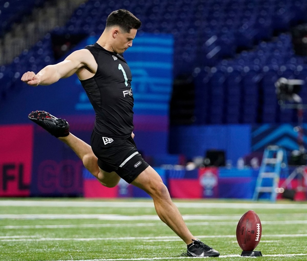 2022 NFL Draft: Matt Araiza in black workout clothes about to kick a football on a football field.
