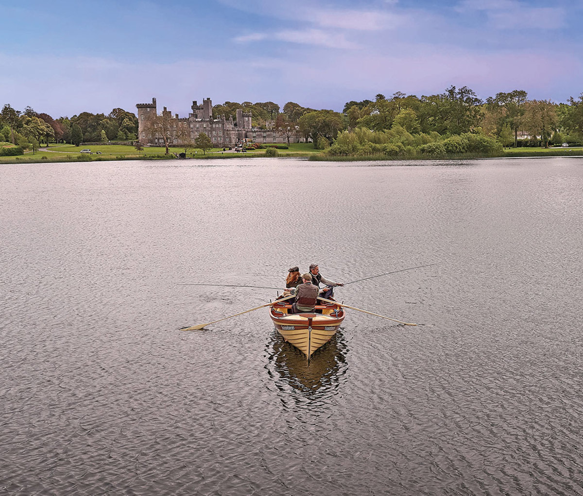 Two people in rowboat heading toward castle