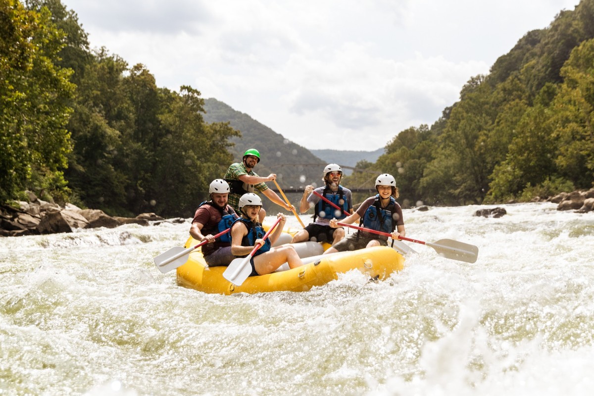Group of young adults whitewater rafting in rapids