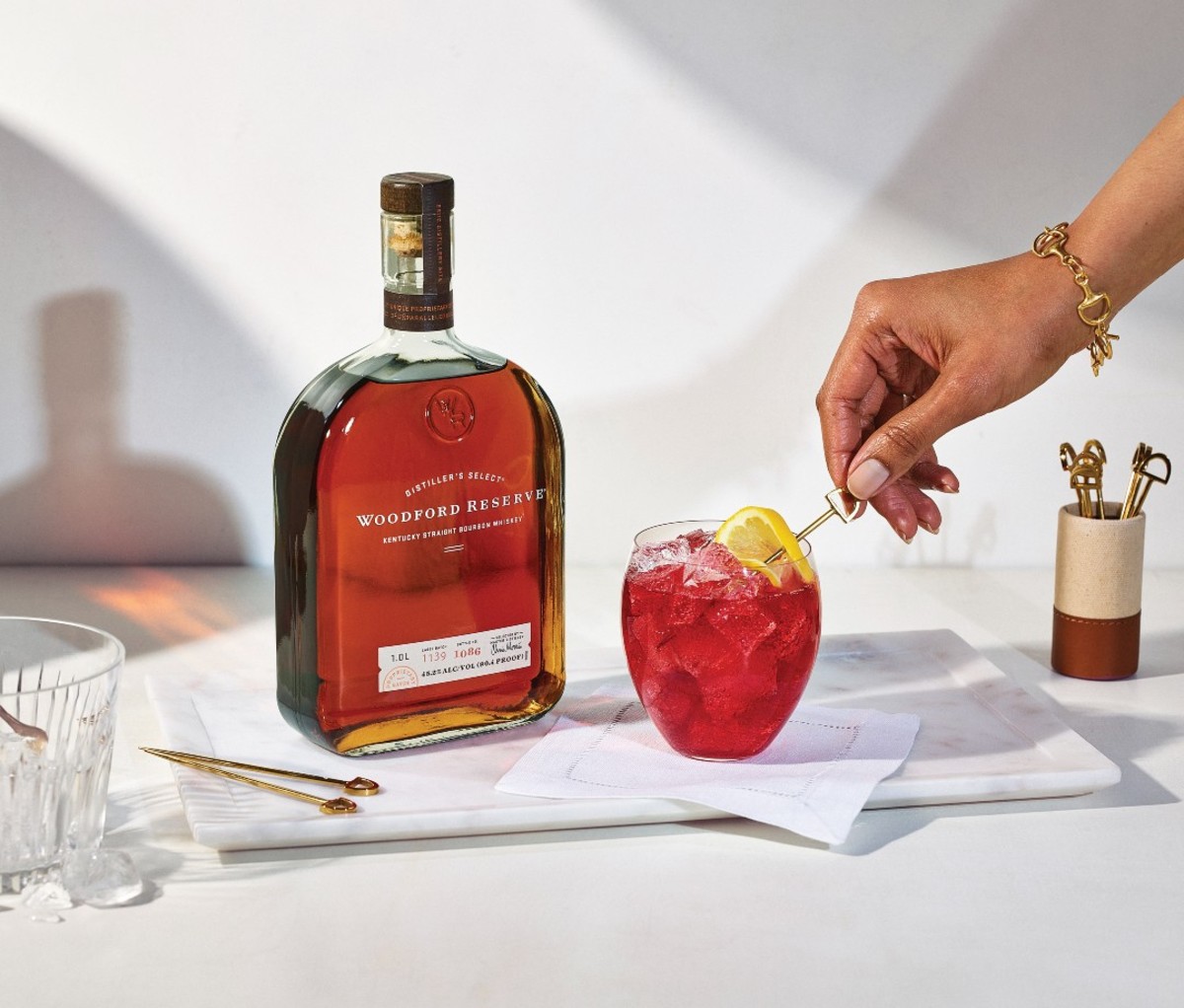 How to Make the Official $1,000 Kentucky Derby Bourbon Mint Julep: 2022 3 Bottle of Woodford Reserve next to cocktail
