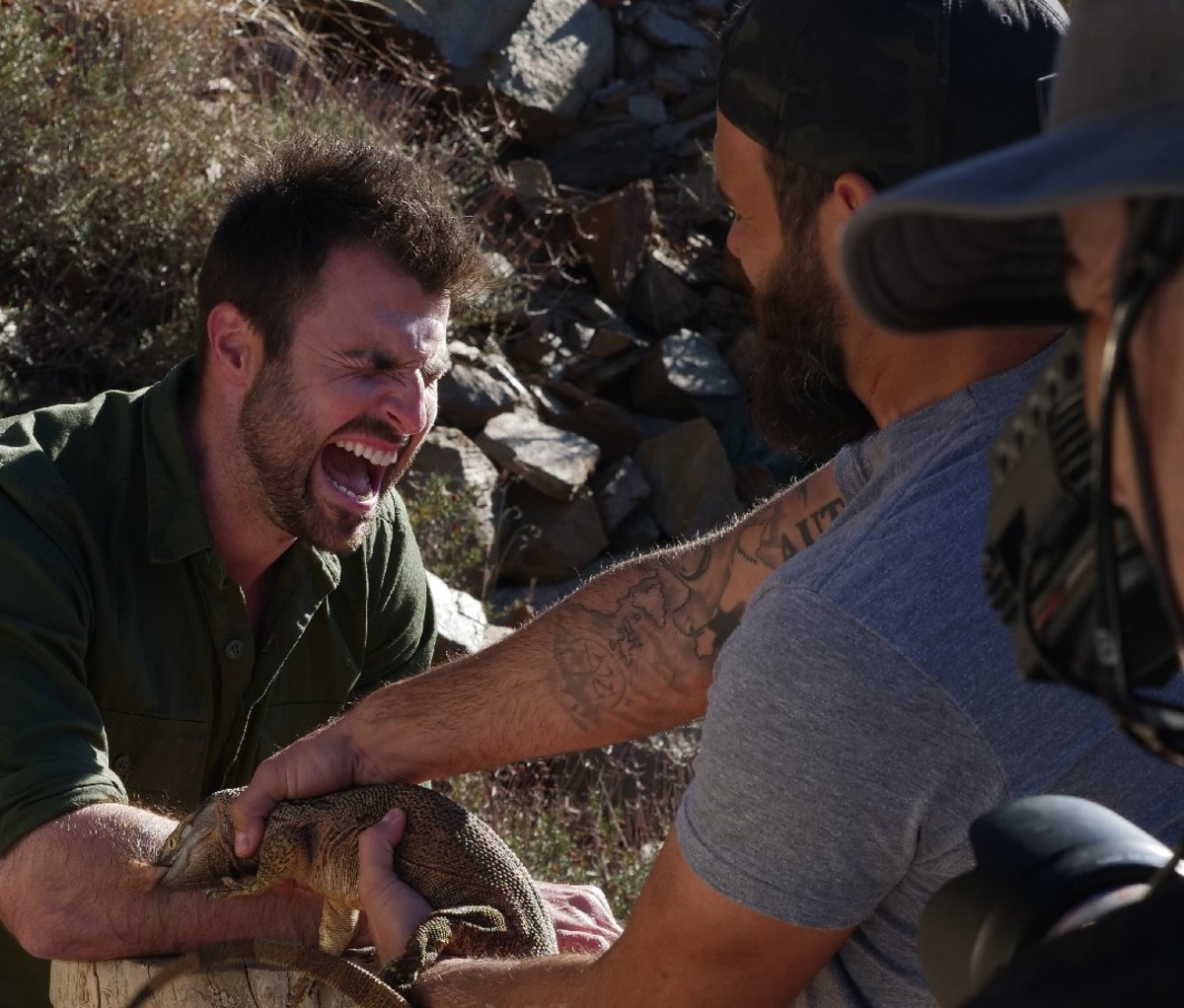 'Kings of Pain' co-host Adam Thorn screaming while Adam Thorn holds a lizard biting his arm.