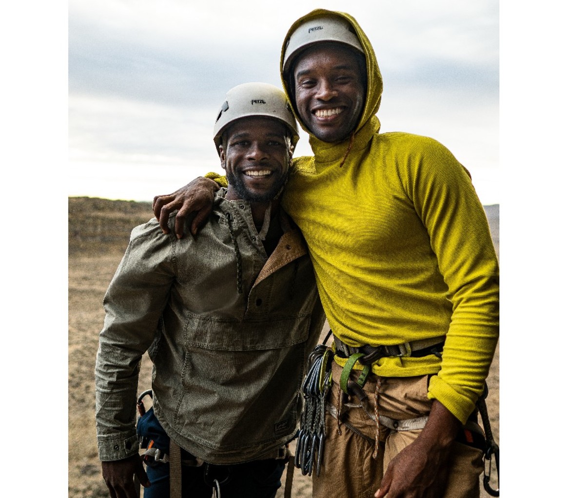 Two smiling helmeted hikers smile for the camera with an arm around each other
