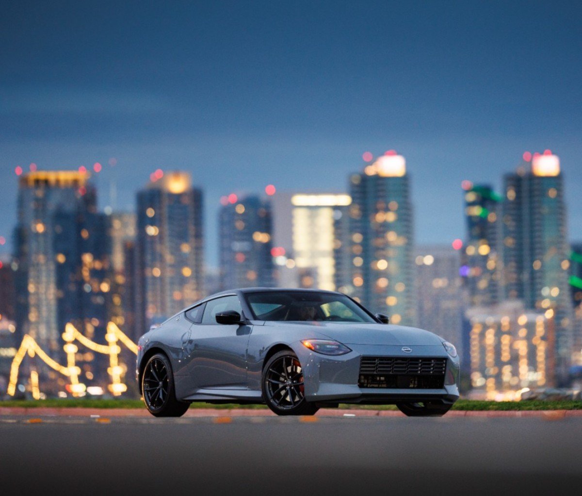 Grey sports car in front of skyline at sunset