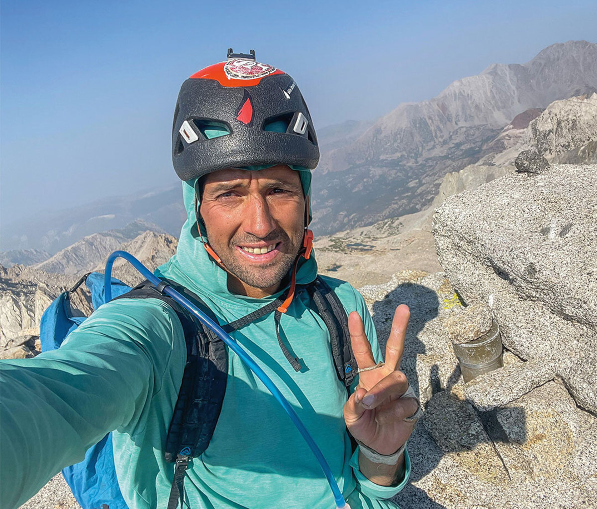 Climber in blue jacket and helmet signing peace with hands