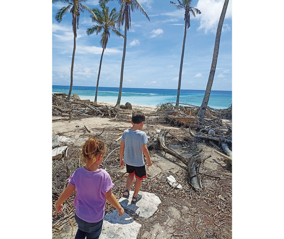 Young boy and girl walking on tsunami-wrecked beach