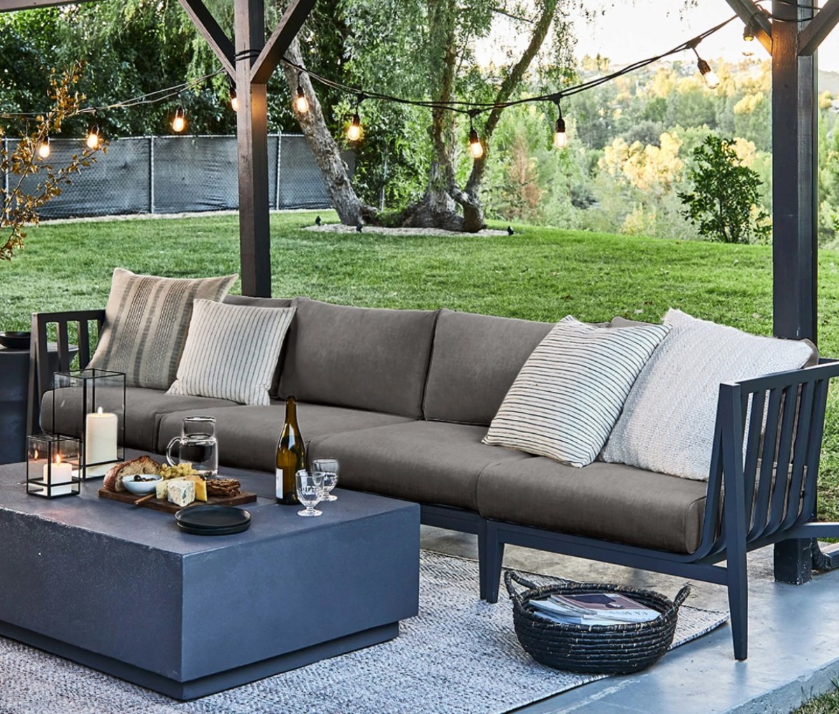Grey outdoor furniture with wine bottles and glasses on concrete table