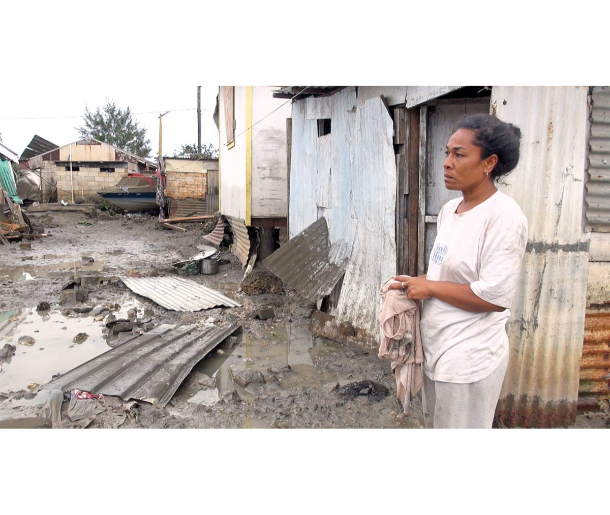 Polynesian woman standing in front of tsunami wreckage