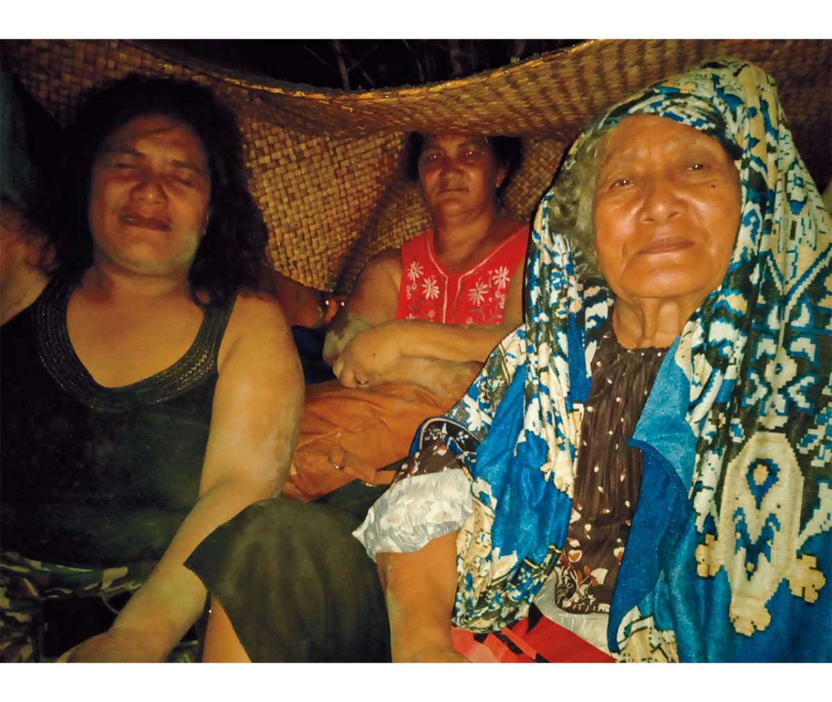 Polynesian natives seeking shelter under mat