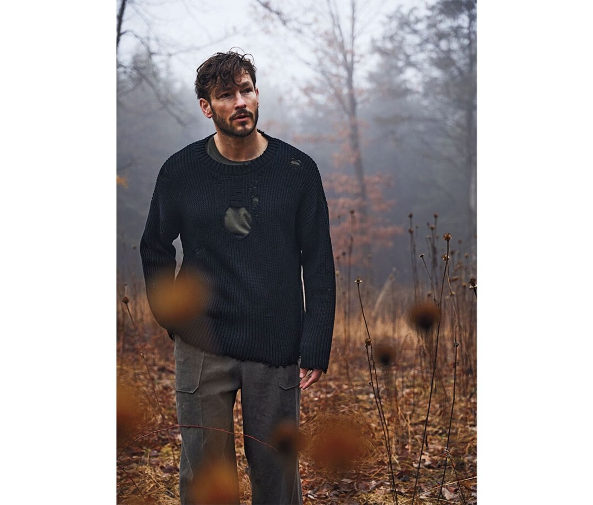 A man in the woods wearing a black sweater