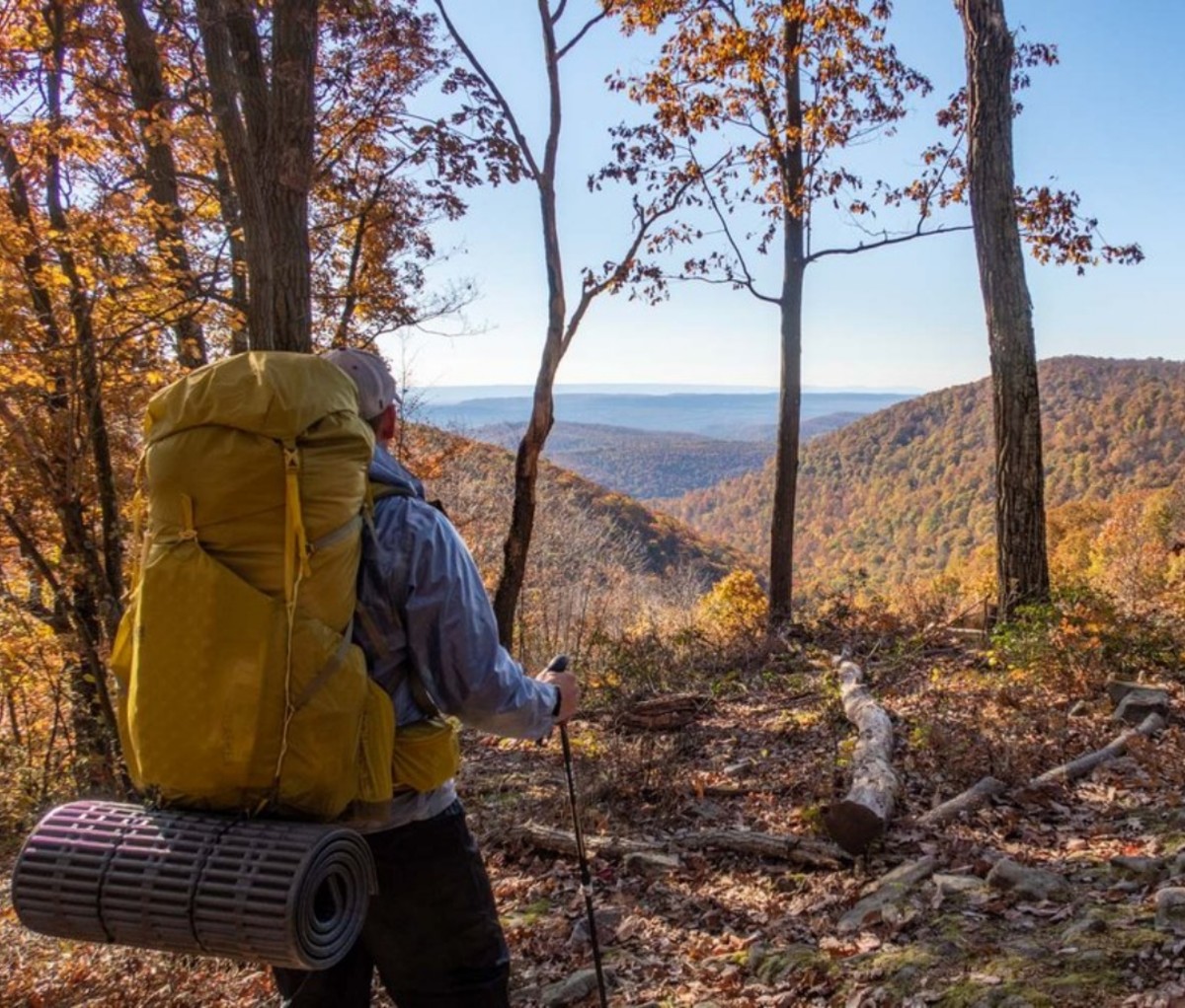 Backpacker looking out over rolling mountains in the distance in autumn