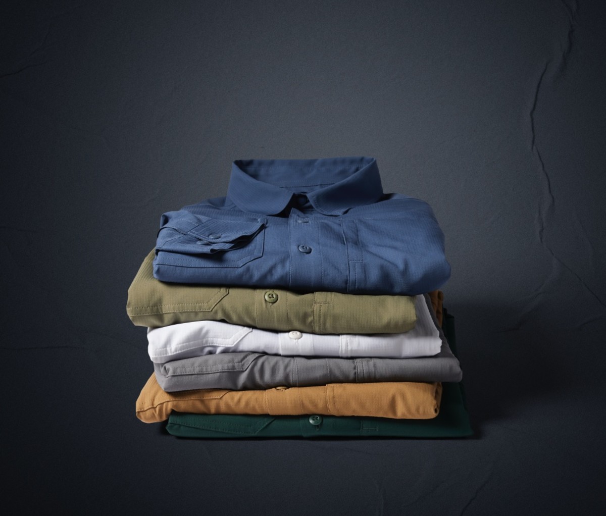 Multicolored Columbia Silver Ridge Utility Collection shirts folded and stacked against a black background.