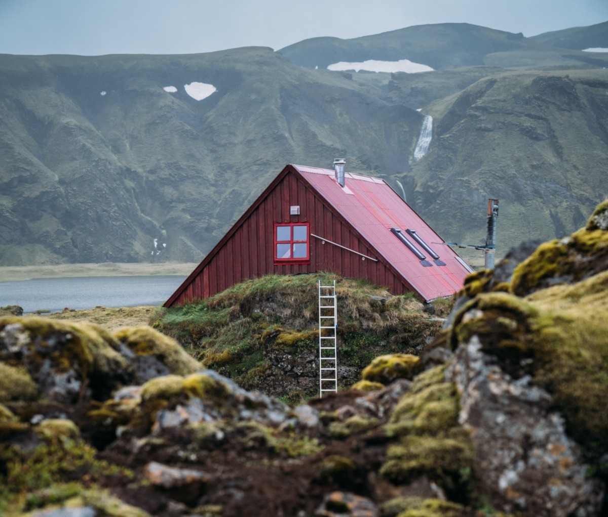 Red building behind moss-covered rocks. Iceland, 57hours