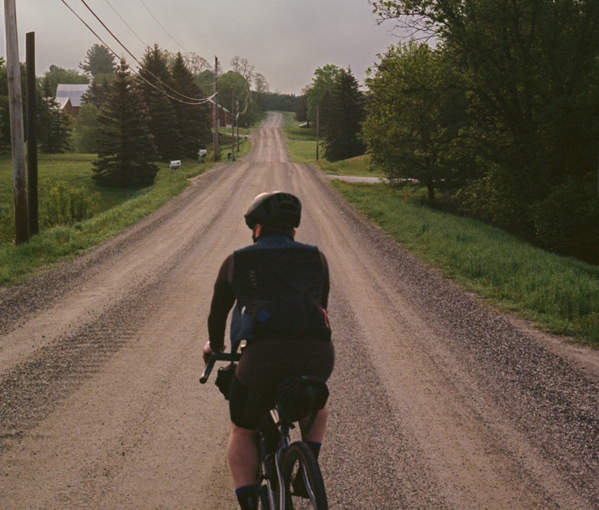 Man riding a bike along a gravel road. new england bikepacking