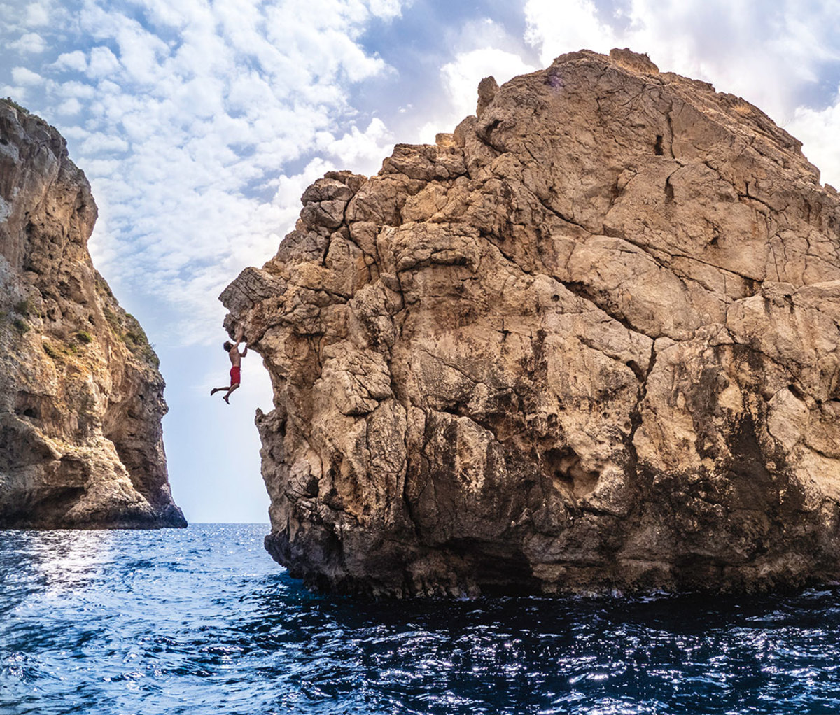 Rock climber hanging on limestone rock over water