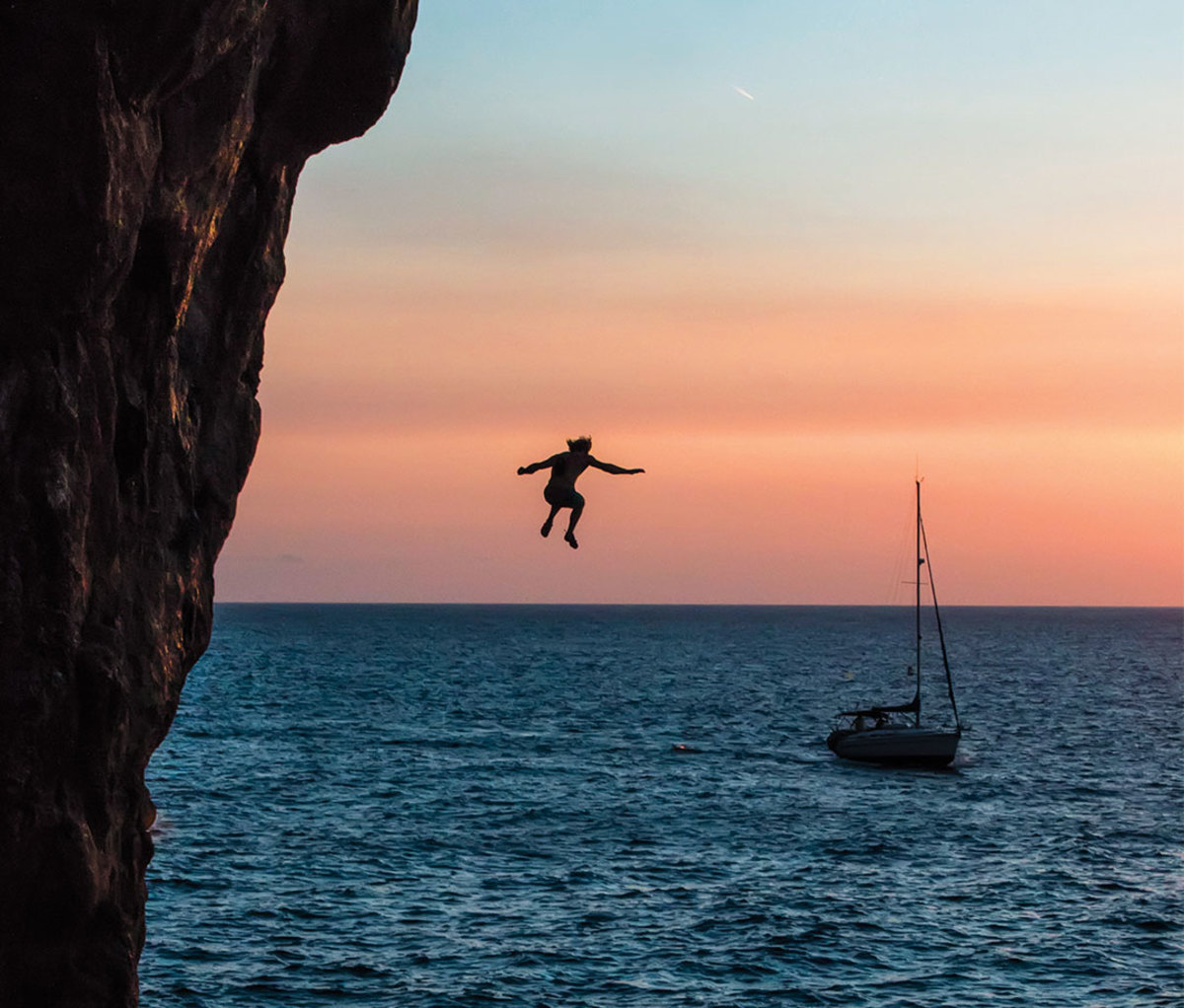 Rock climbing falling into water at sunset