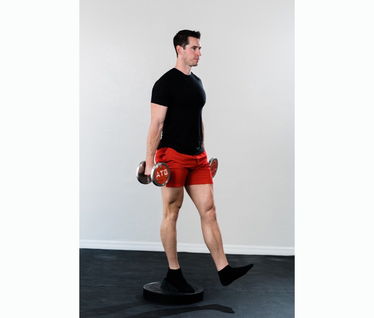 Caucasian man in black T-shirt and red shorts doing Poliquin stepup