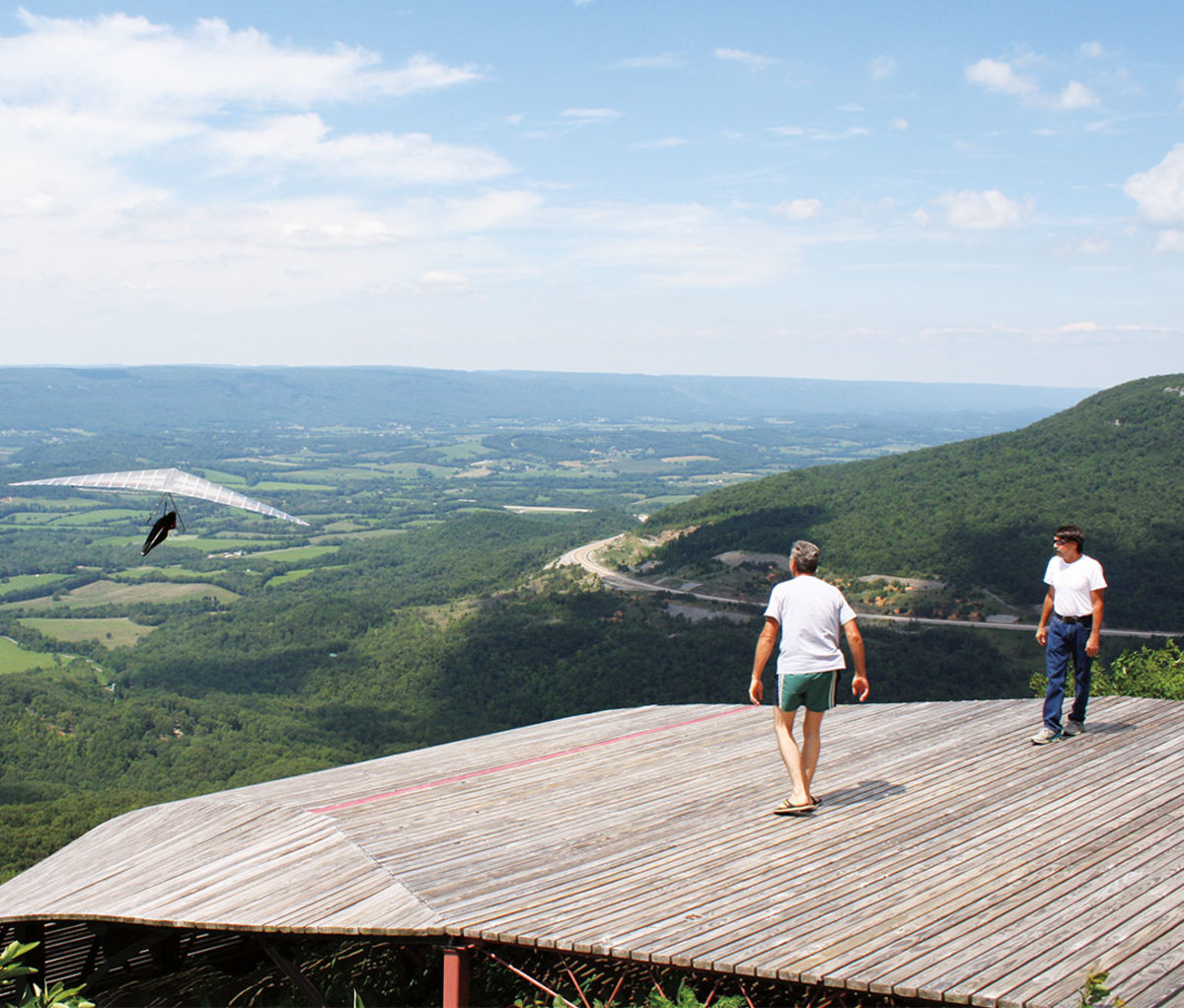 Two men look on at paraglider