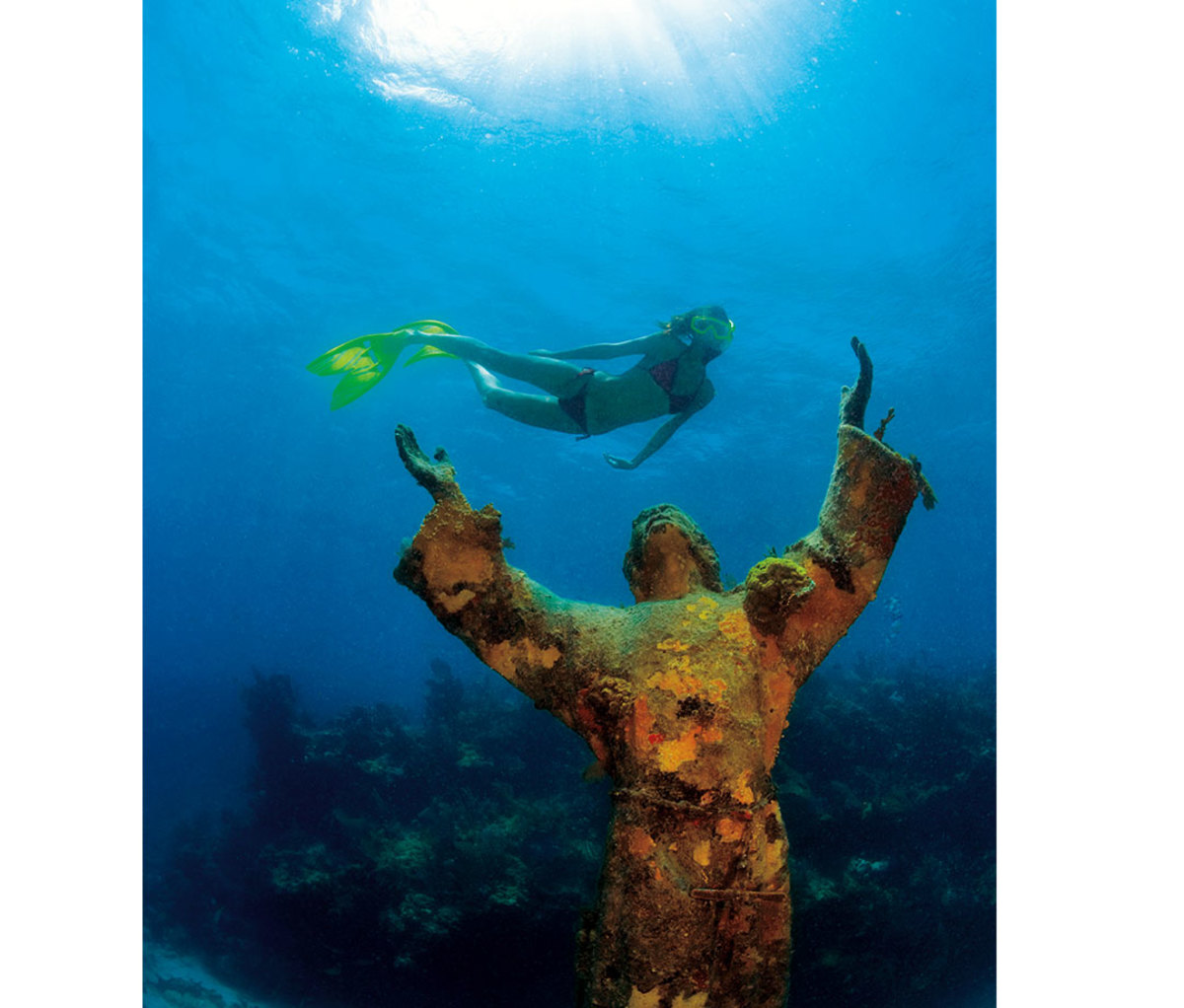 Woman scuba diving past wreckage