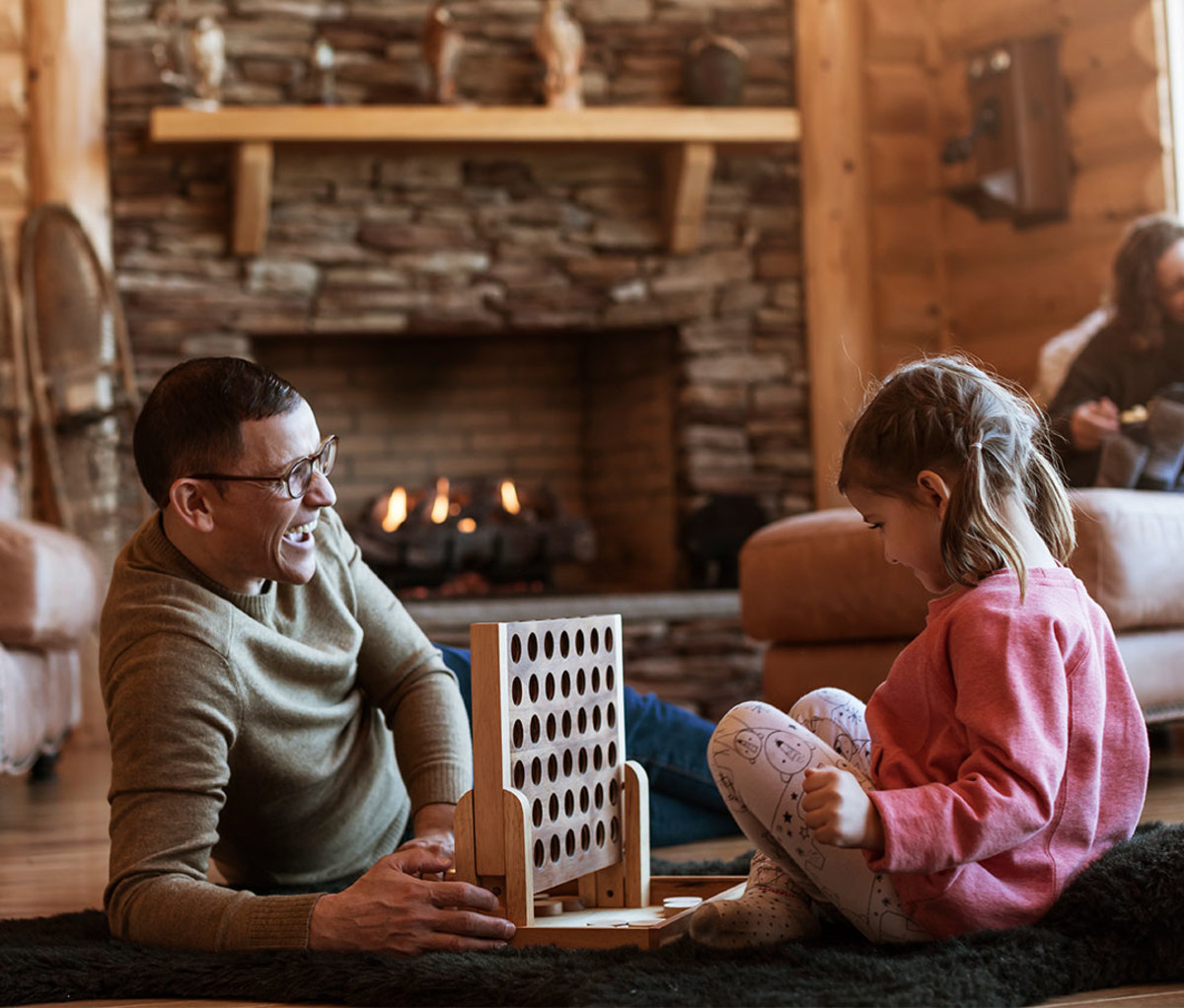 Father playing Connect Four game with daughter in cabin