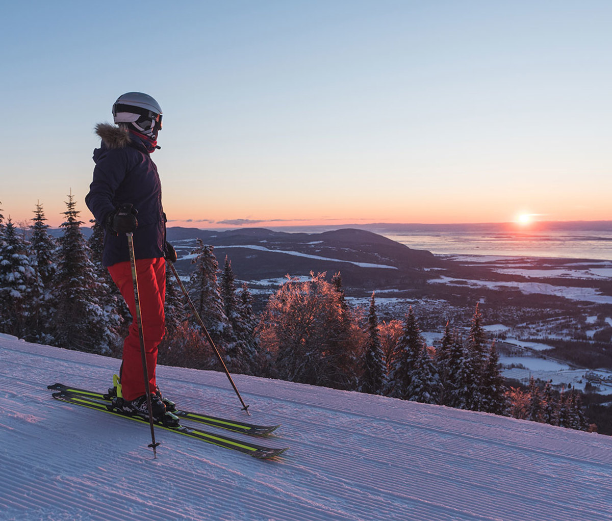 Female skier looks out at sunset