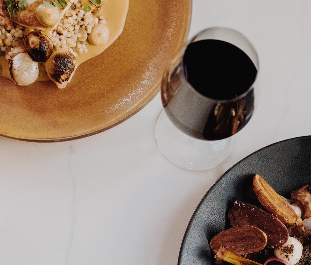Overhead view of glass of red wine with entree and dessert