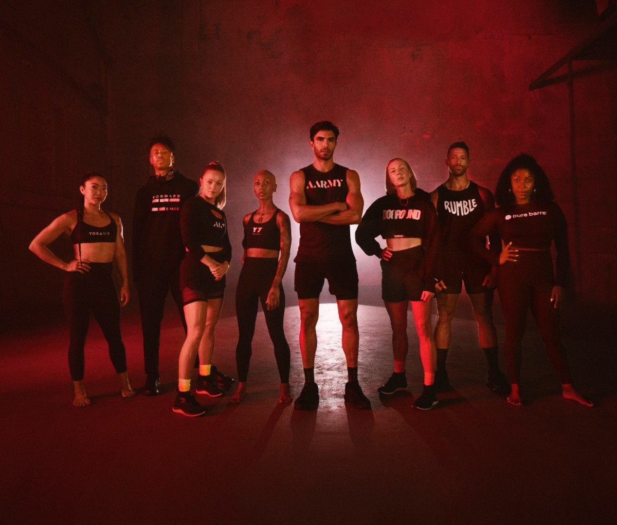 Group of male and female fitness instructors standing in red-hued light