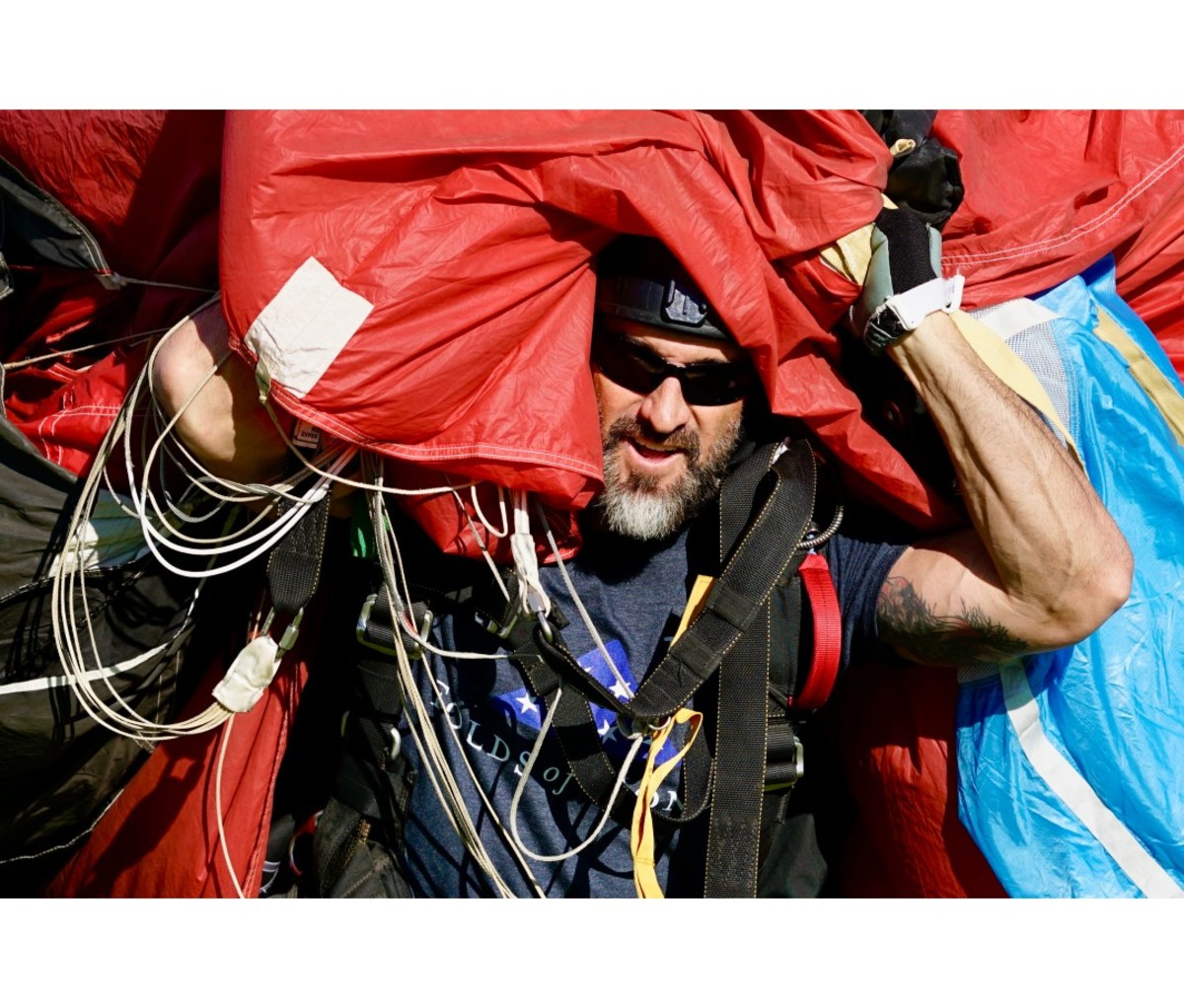 Caucasian man carries red parachute
