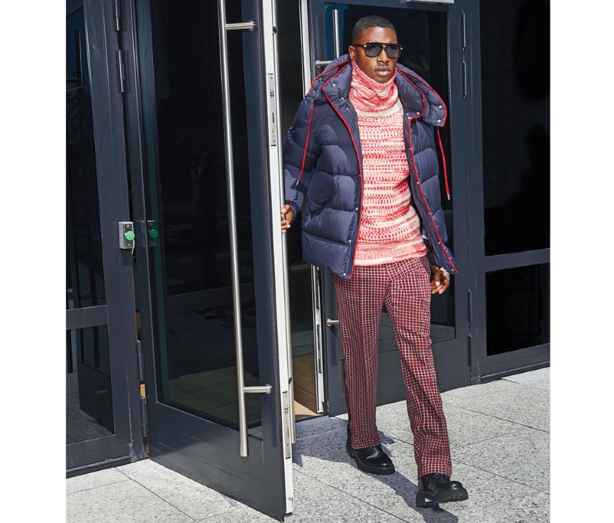 A man wearing a puffer coat exits a building.
