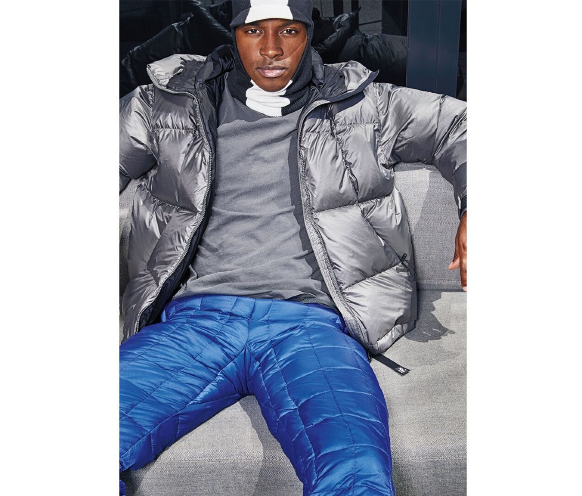 A man wearing many puffer clothing pieces sitting.
