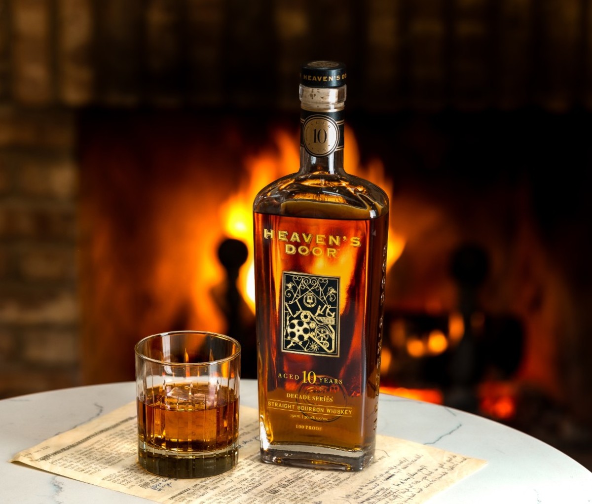 Bottle of whiskey with glass half full in front of fireplace