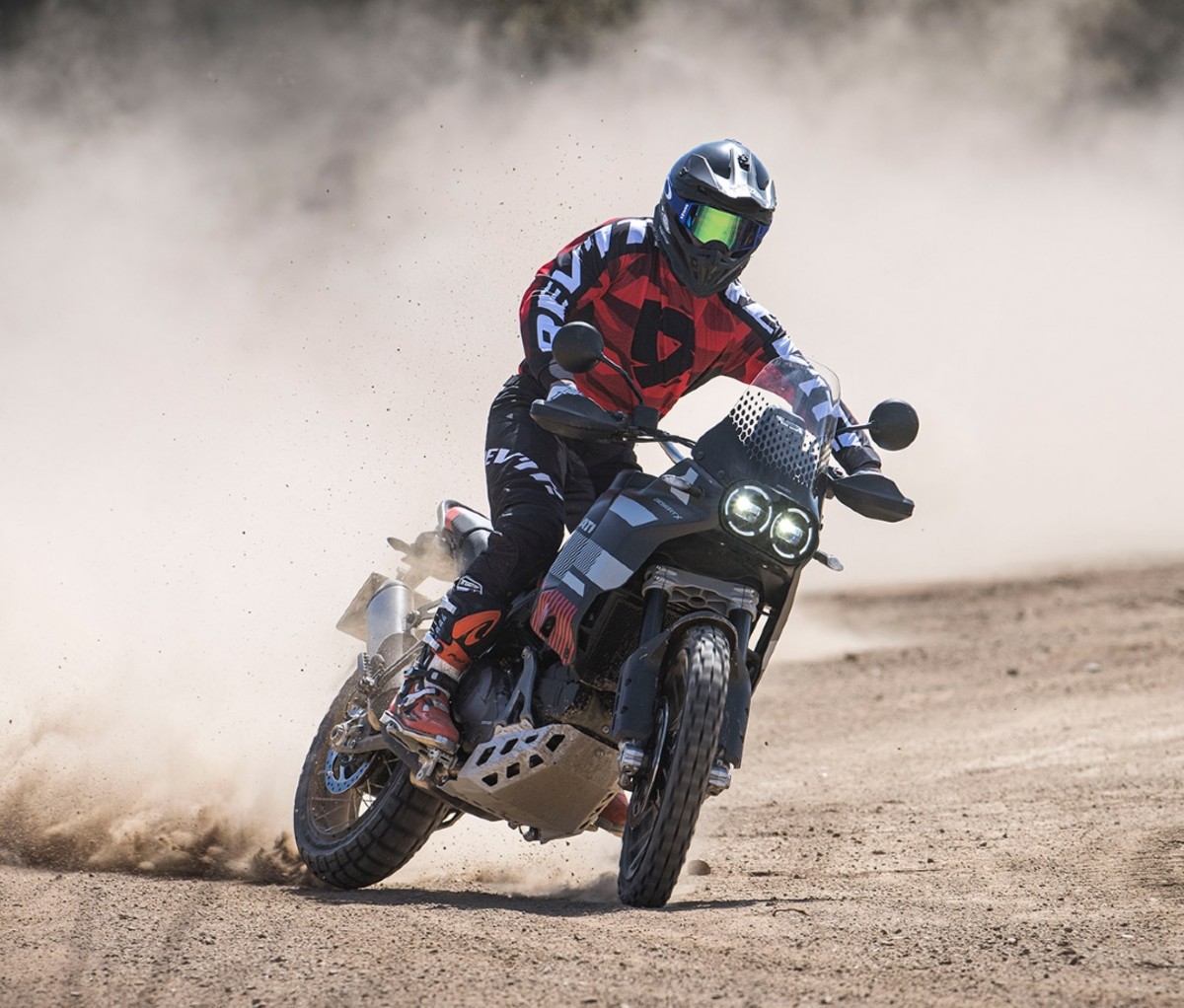 Adventure motorcycle with rider taking a sliding turn on a dirt track.