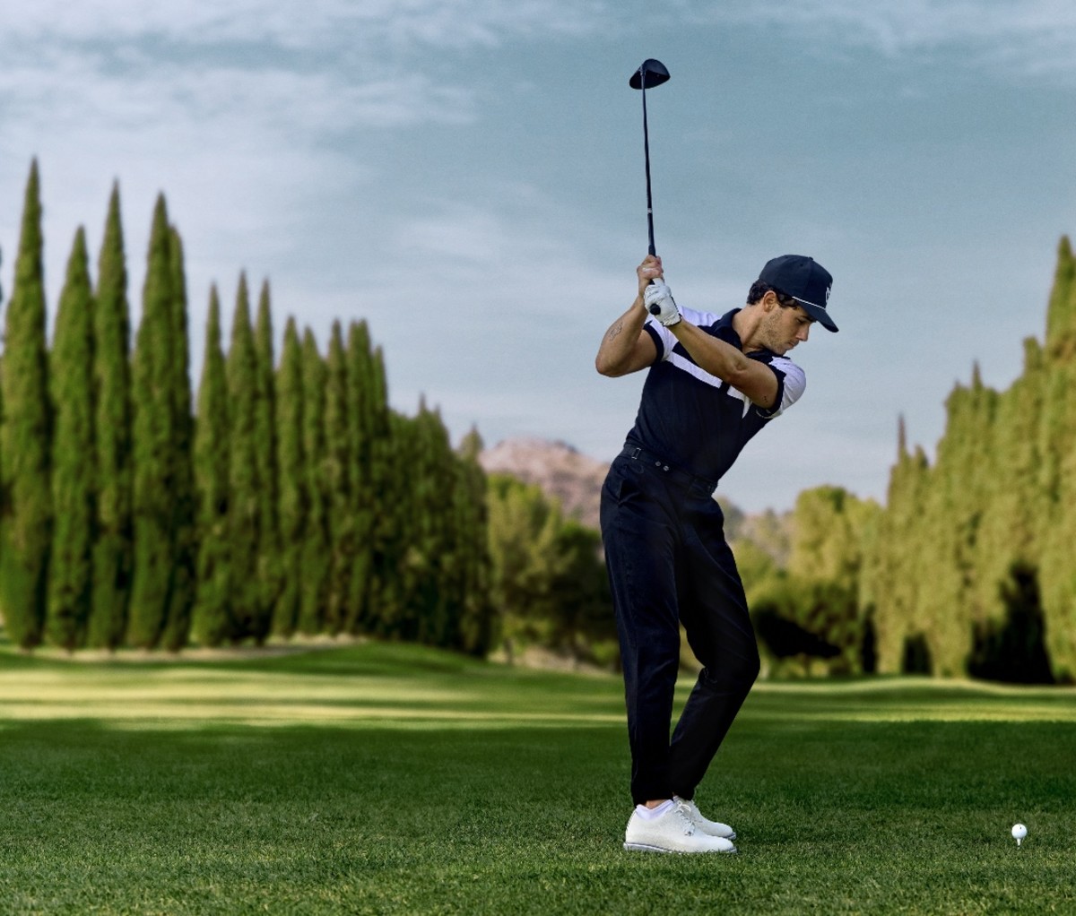 Actor Nick Jonas swinging golf club on course