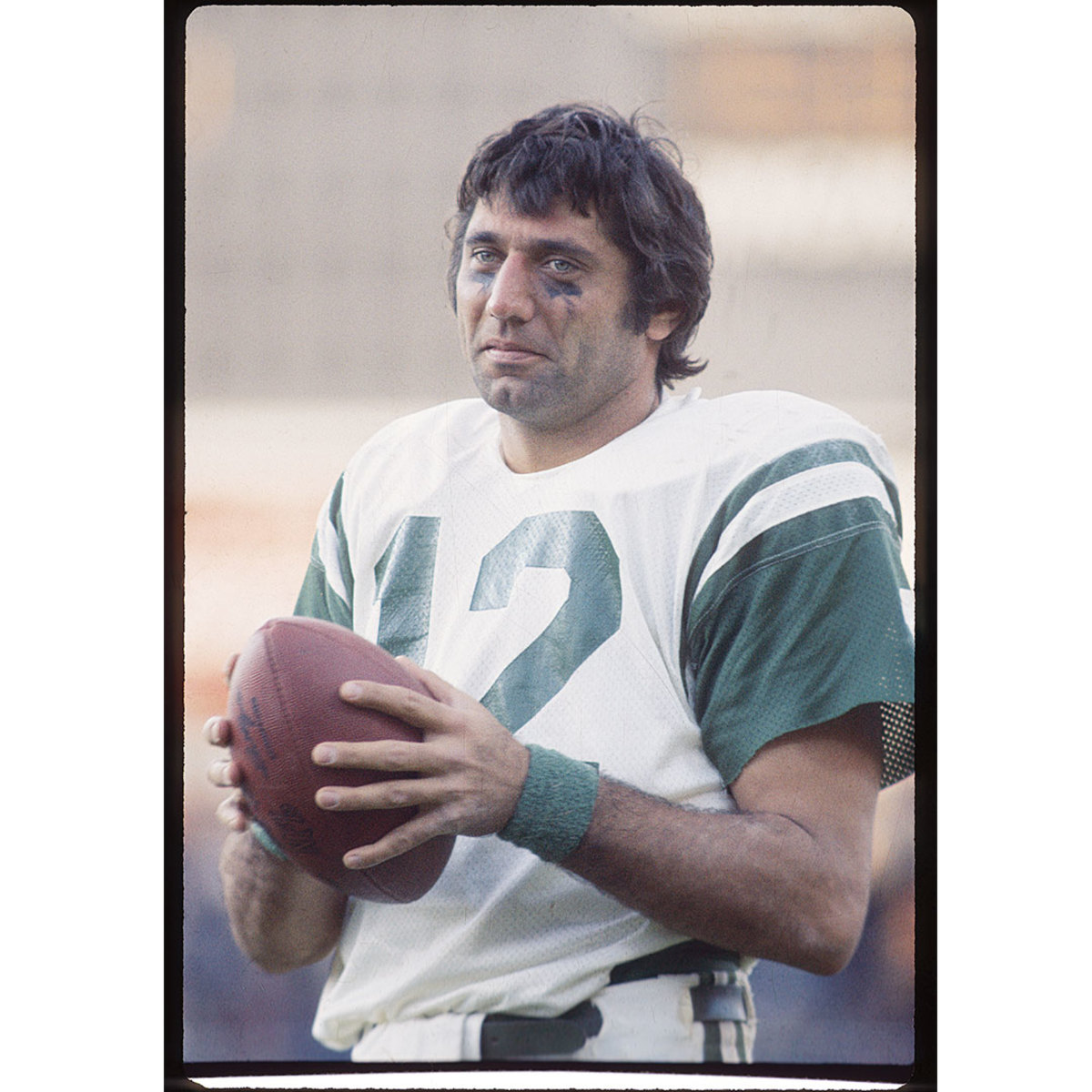 Portrait of football player in green and white jersey holding football