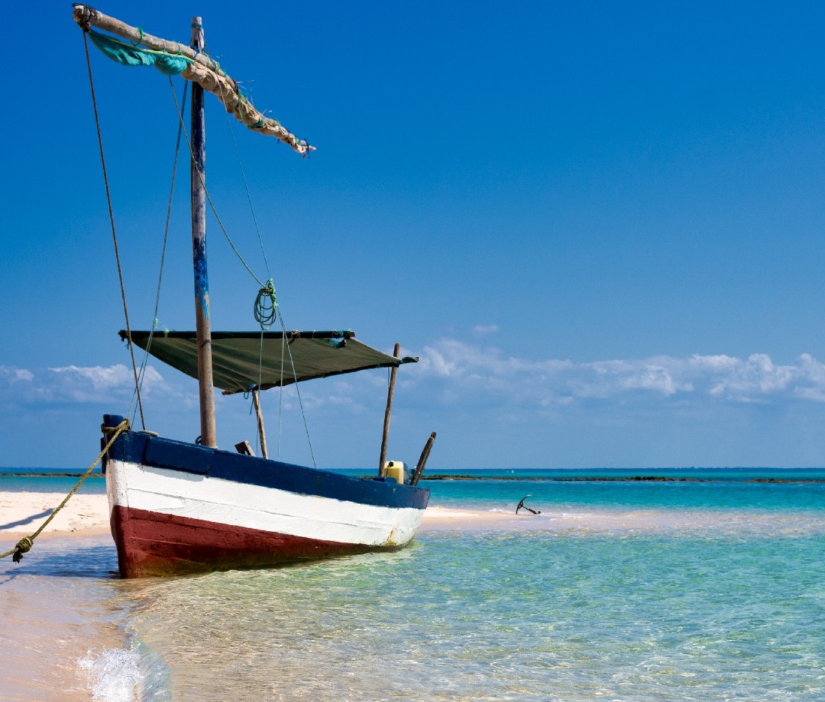 Dhow sailboat parked on a sandy shore in Mozambique.