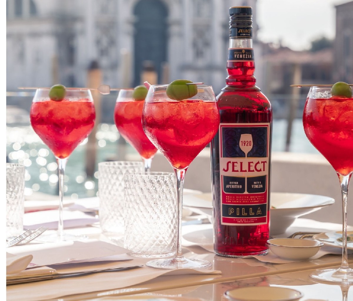 Four Select spritzes on an outside table next to the bottle in Venice.