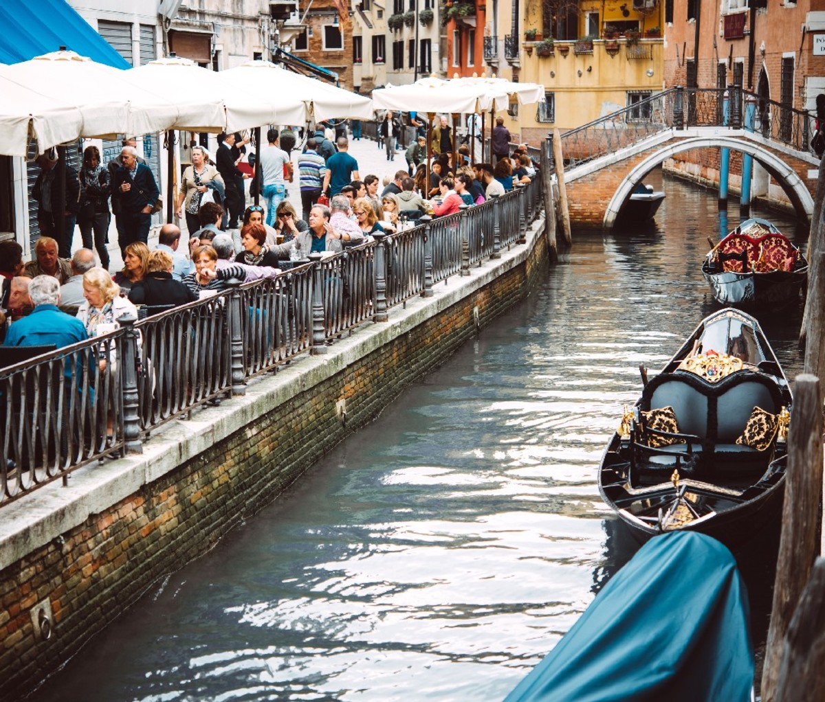 Peopled Venice cafe next to a canal.