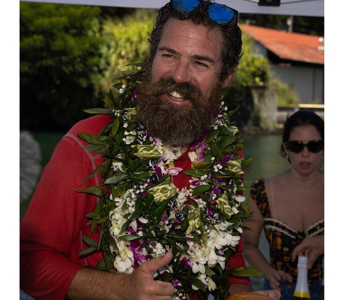 Cyril Derreumaux headshot, smiling in Hawaii with a lei around his neck.