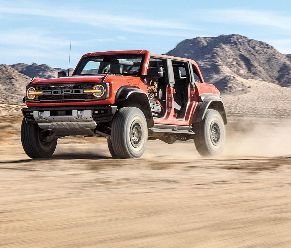 Orange Ford Bronco 4x4 speeding over dusty desert