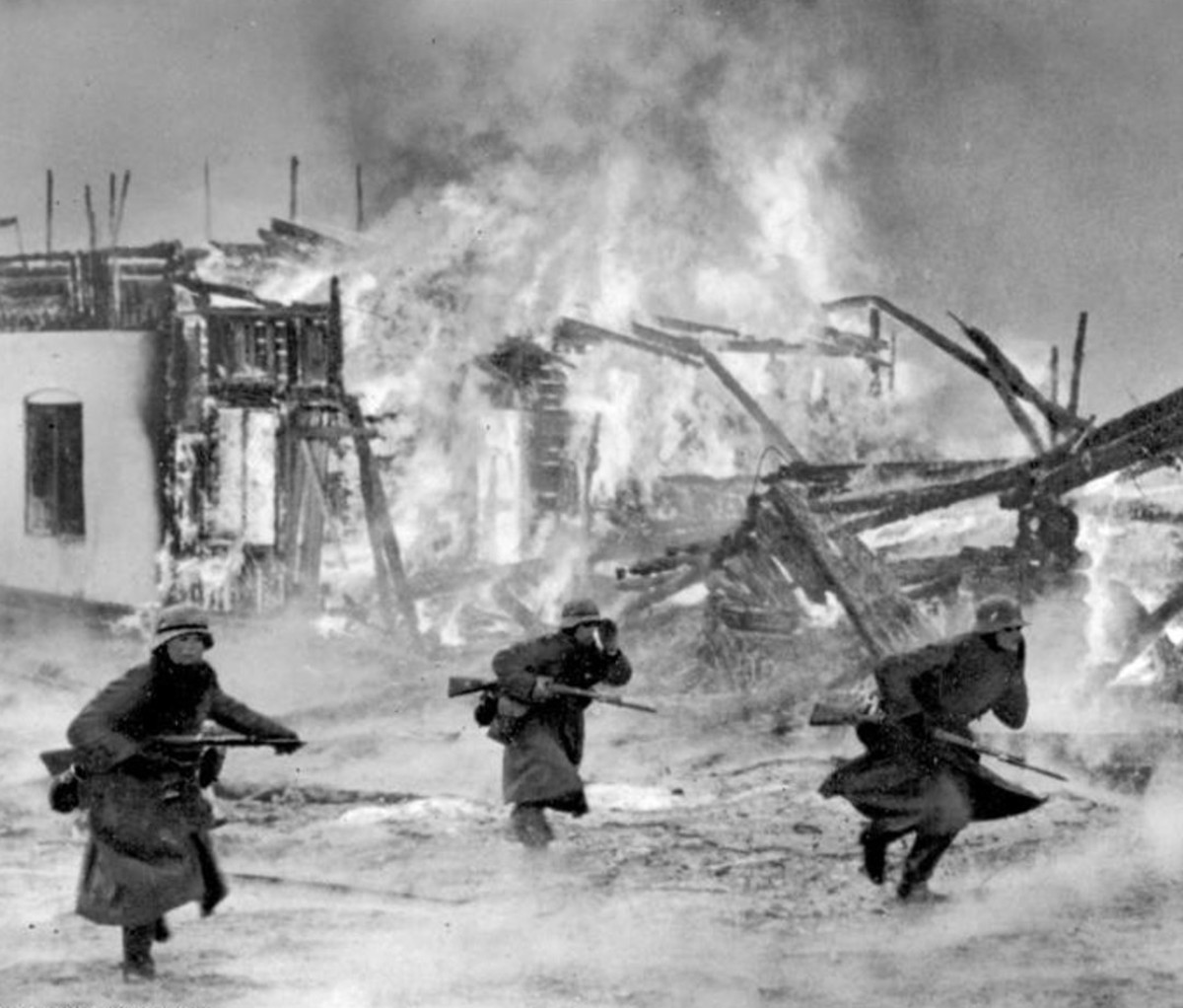 Black and white photo of three men burning town