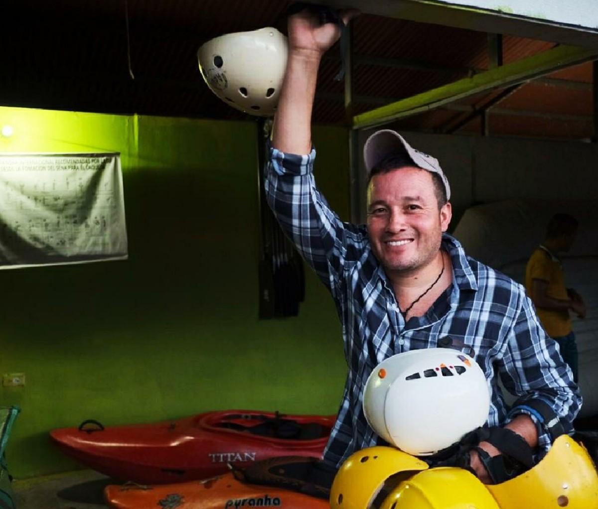 Frellin Alberto Noreña smiling with a pile of rafting helmets in hand.