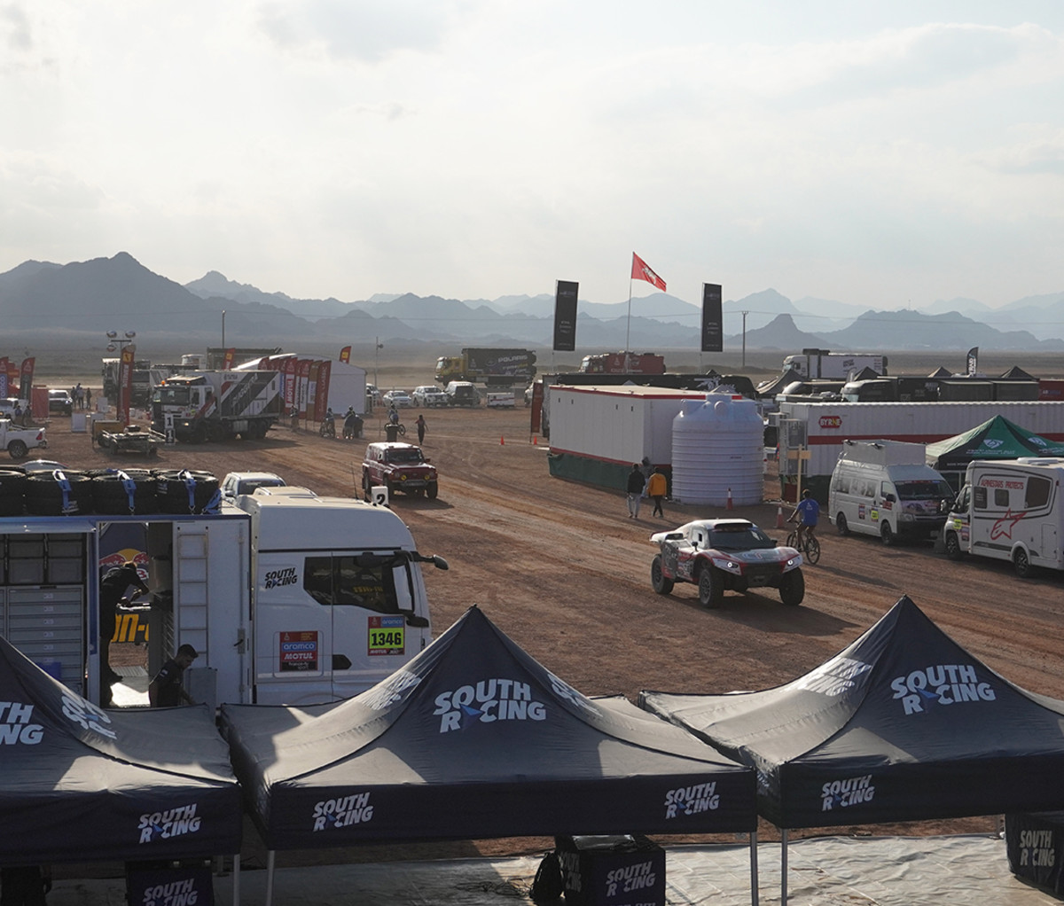 Array of off-road big rigs at the Dakar Rally in a bivouac in the desert.