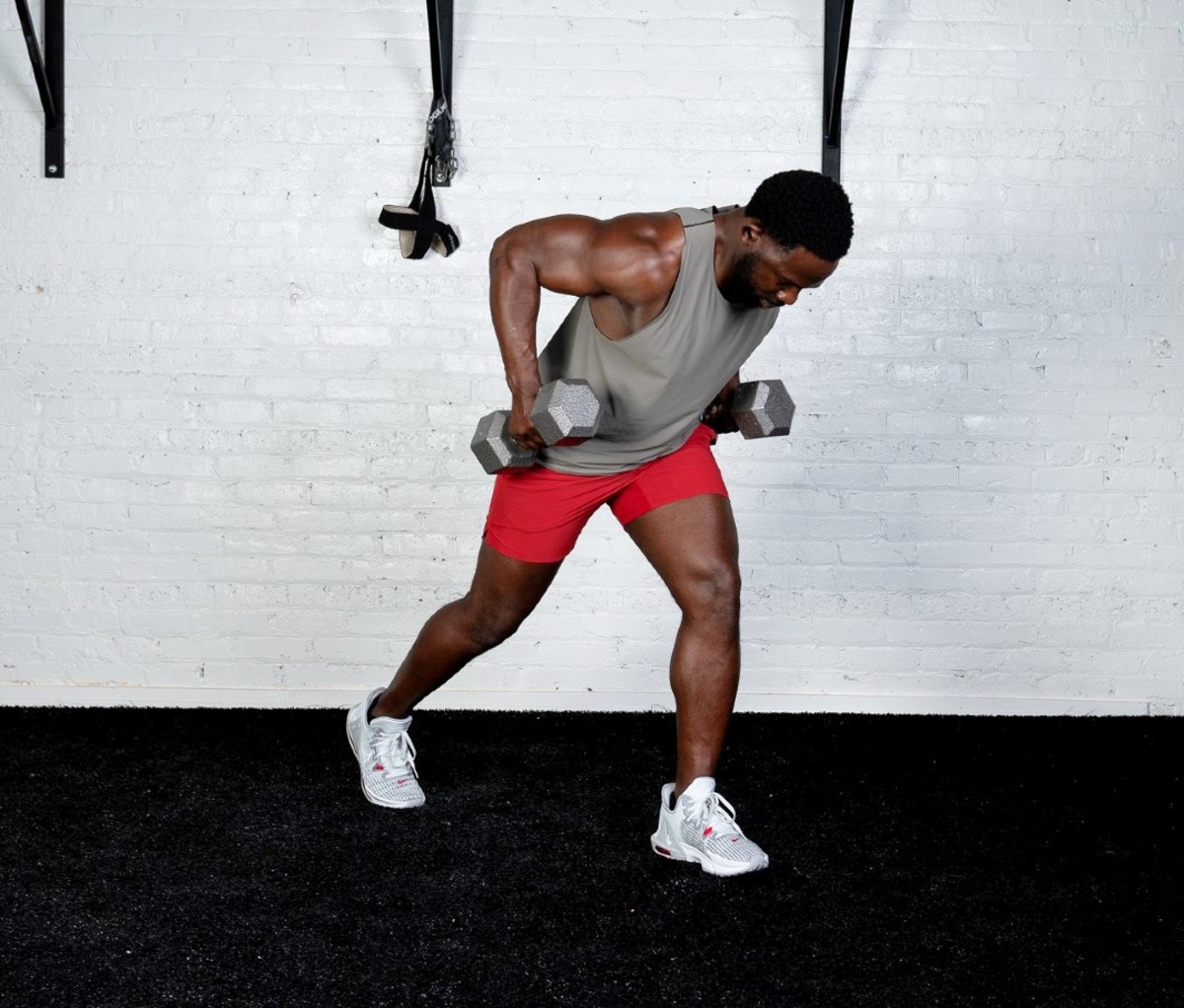 Black man wearing gray tank and red shorts doing Staggered-stance Unilateral Bentover Row