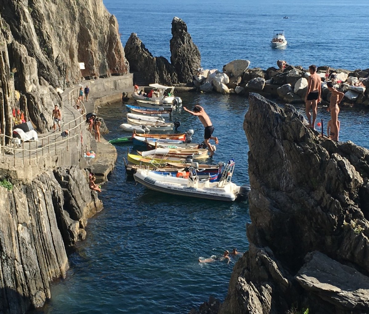 Un locale si tuffa da una scogliera in acqua sulla costa di Manarola