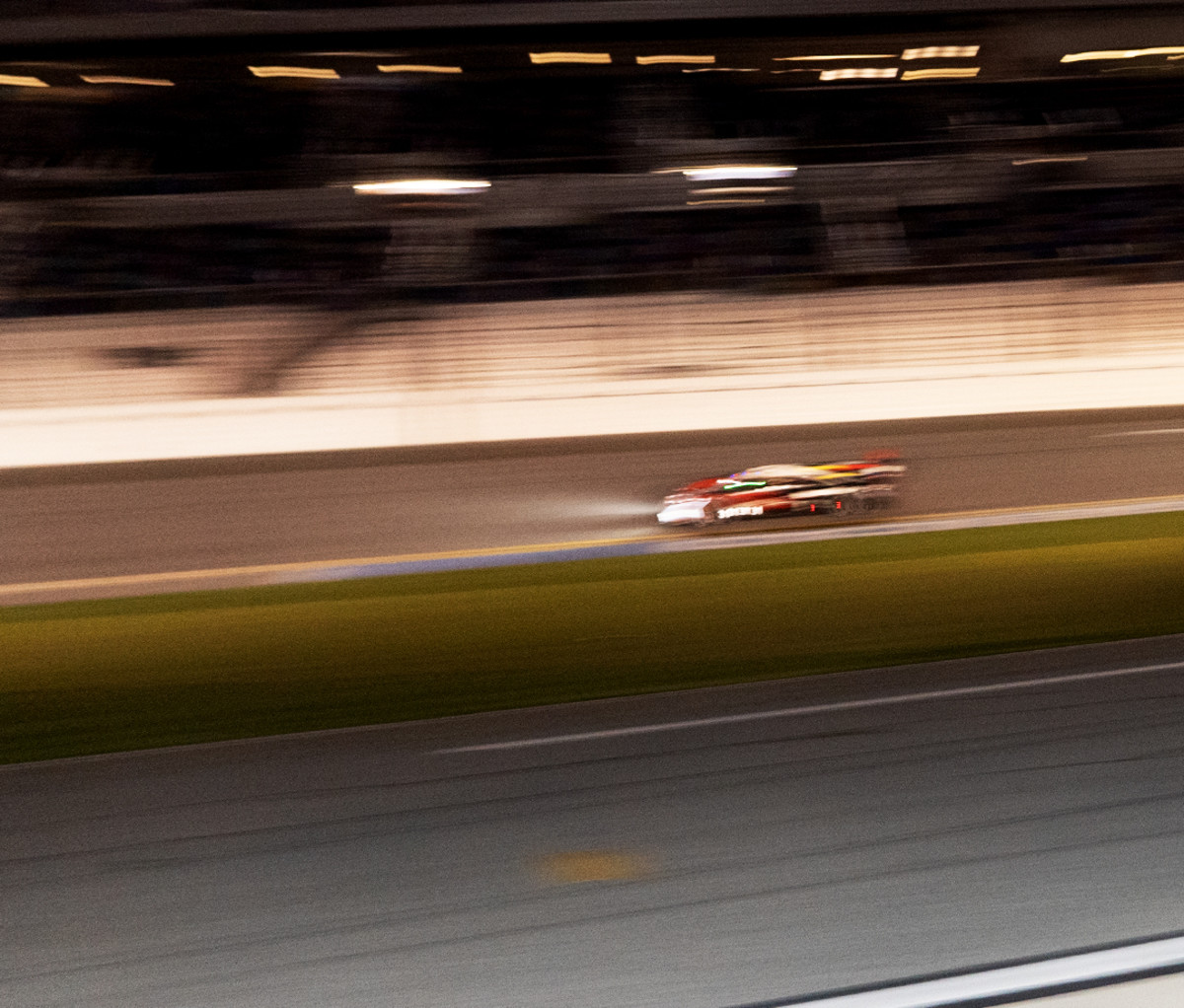 Blurry shot of a racecar driving at night at Daytona Speedway.