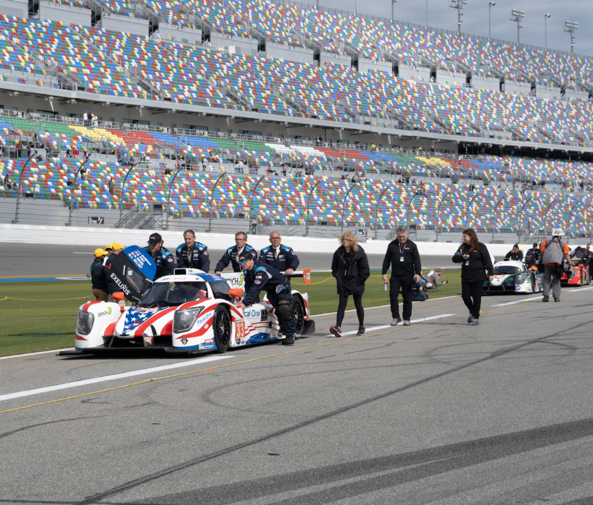 Racecar drivers walking to a racecar on the track at Daytona Speedway.